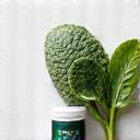 Maliit na bote ng iron supplement sa tabi ng sariwang spinach.